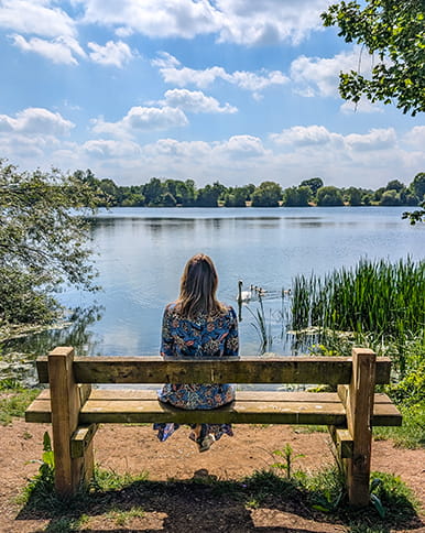 A woman sitting on a bench in front of a lake