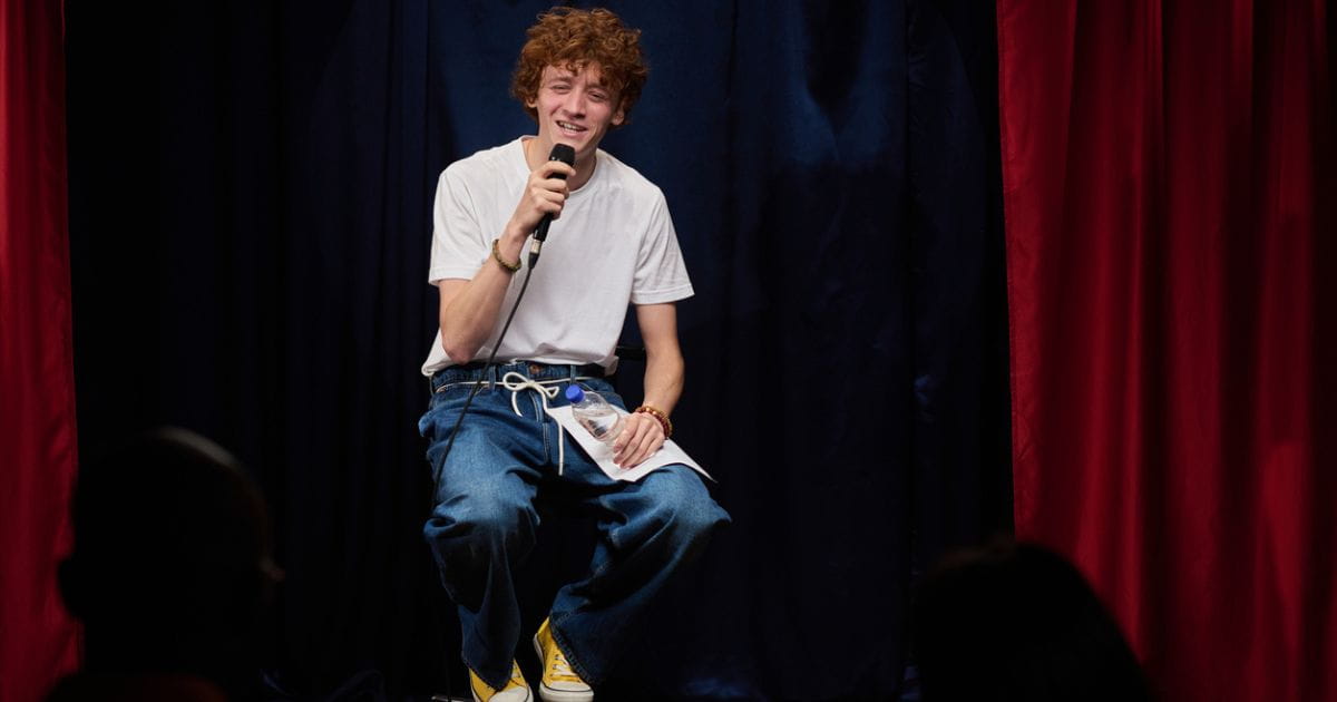 Stock image of a man on a stool doing comedy at a venue