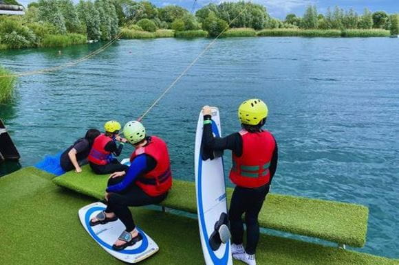 People wearing wetsuits doing cable wakeboarding