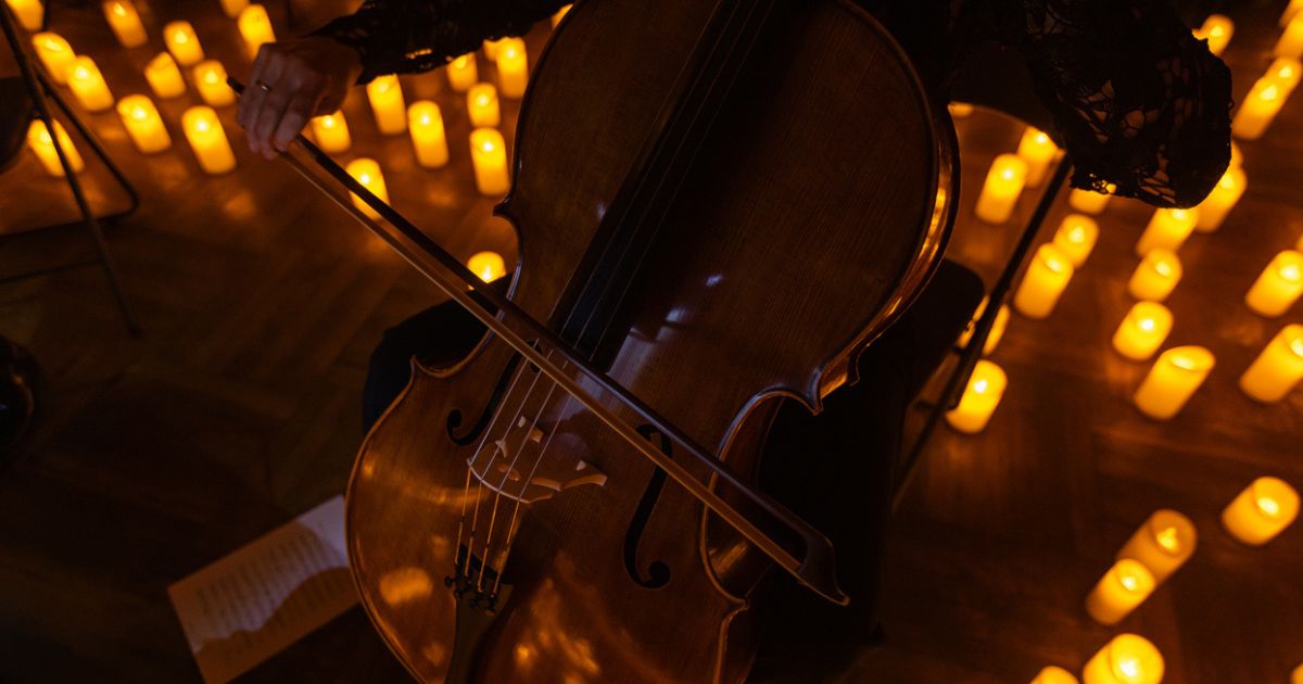 A person playing the cello by candlelight