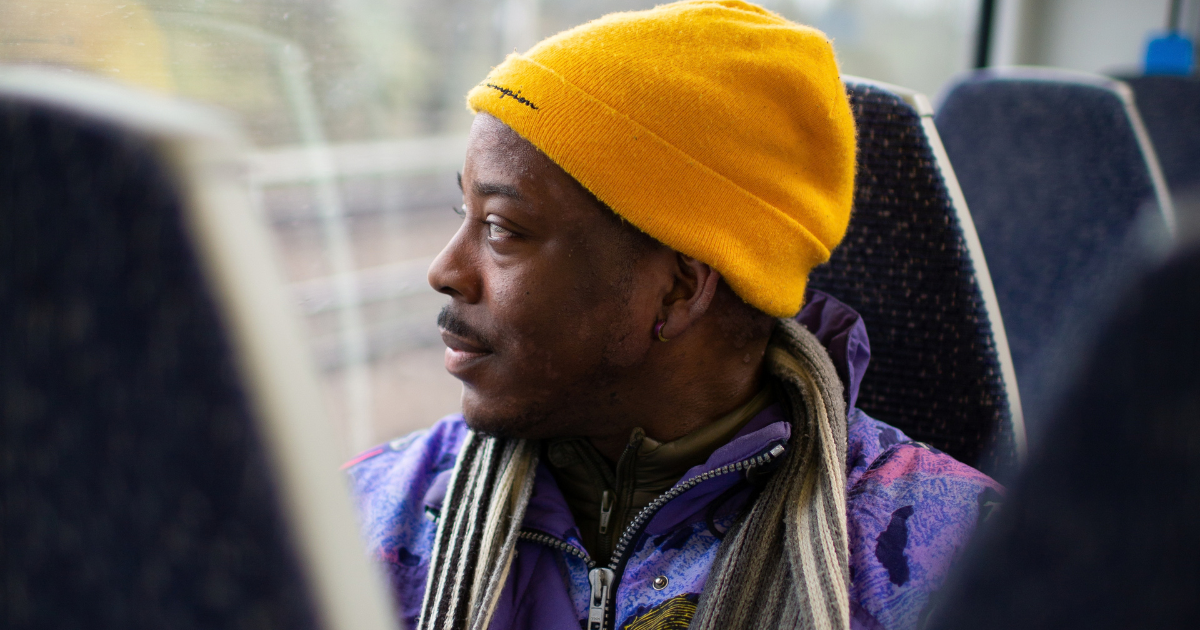 A man wearing a yellow hat looks out the window on a Thameslink train