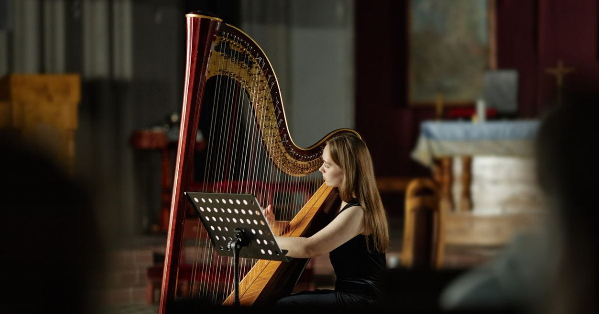 A woman playing a harp in an atmospheric room
