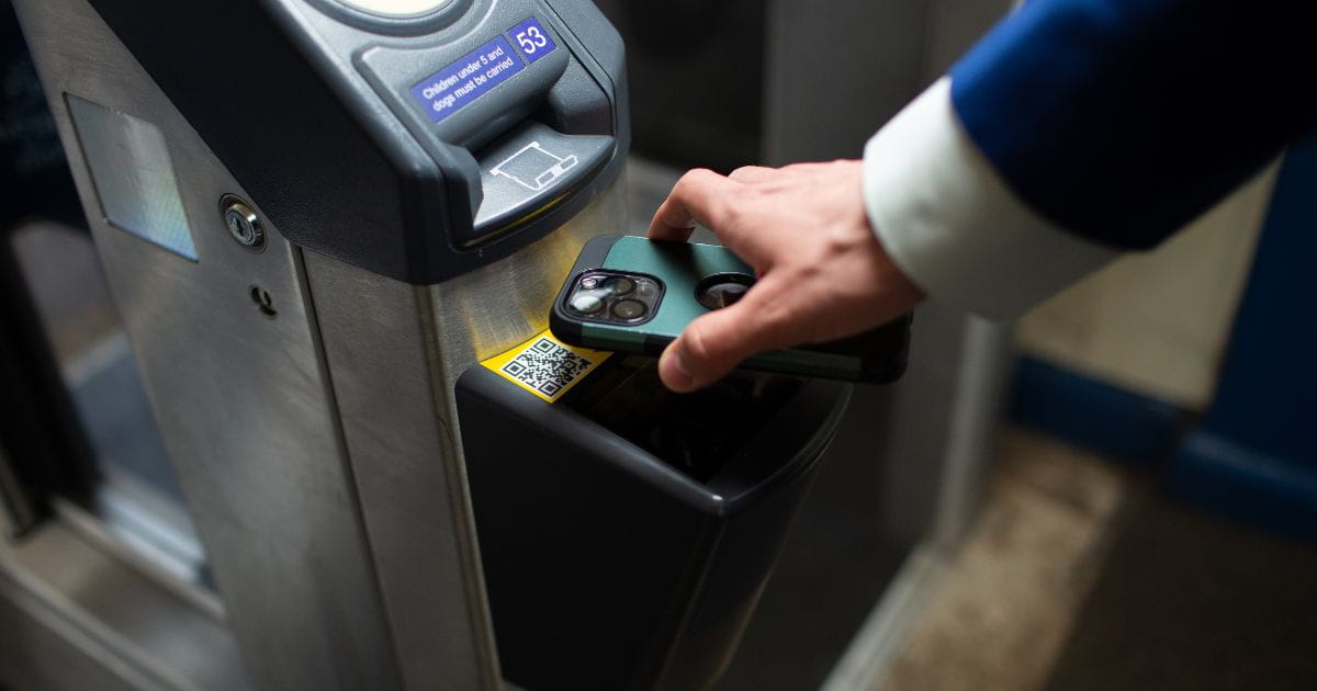 Person scanning a train ticket at a barrier
